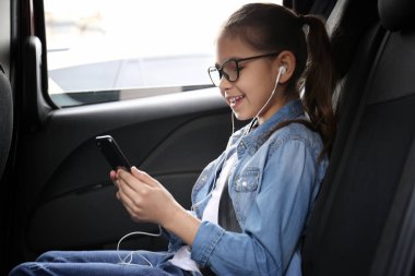 Arabada sesli kitap dinleyen tatlı küçük kız.