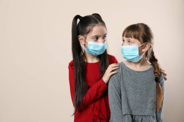 Bej arka planda tıbbi maskeli küçük kızlar, mesaj için yer var. Virüs koruması