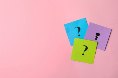 Pembe arka planda soru işaretleri olan kâğıt kartlar, düz yatış. Metin için boşluk