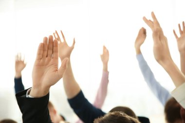 İş eğitiminde insanlar el kaldırarak ışık arkaplanı ve yakın plan hakkında sorular soruyorlar.