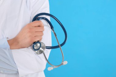 Mavi arka planda steteskoplu genç doktorun yakın görüntüsü, metin için boşluk