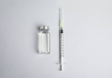 Işık arka planında şişe ve şırınga düz yerde. Aşılama ve aşılama