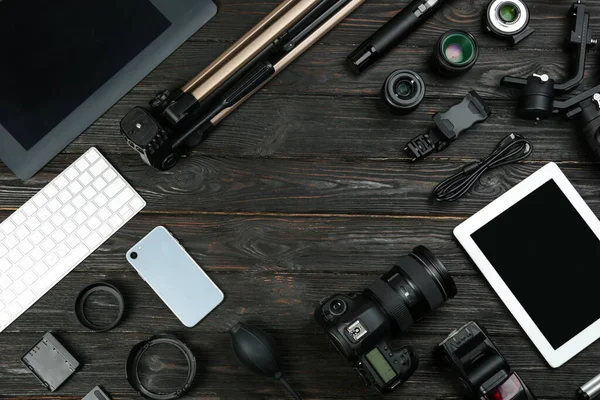 Flat lay composition with camera and video production equipment on black wooden table