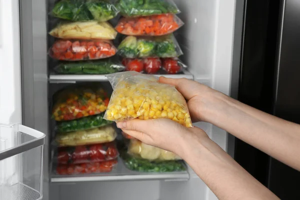 Женщина Держит Пластиковый Пакет Замороженной Кукурузой Рядом Открытым Холодильником Крупным — стоковое фото