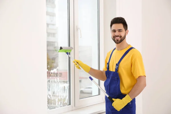 屋内の均一なクリーニングウィンドウ内のプロの若い清掃員 — ストック写真