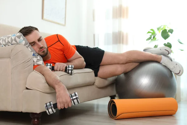 Pemuda Pemalas Dengan Peralatan Olahraga Sofa Rumah — Stok Foto