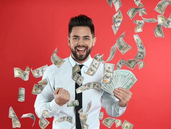 Happy young man with money on red background