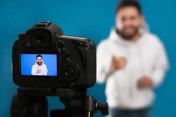 Jovem Blogueiro Filmando Vídeo Com Câmera Contra Fundo Azul Foco — Fotografia de Stock
