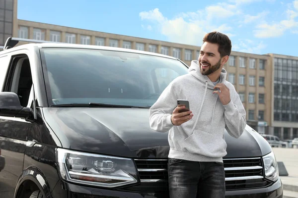 Stilig Ung Man Med Smartphone Nära Modern Bil Utomhus — Stockfoto