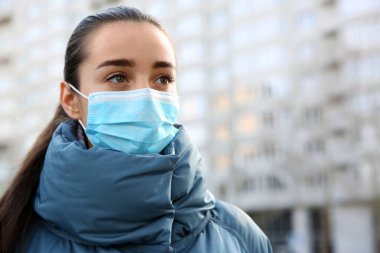 Açık havada tek kullanımlık maske takan bir kadın. Tehlikeli bir virüs.