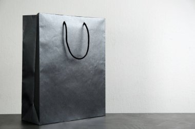 Masadaki siyah alışveriş poşeti, arka plandaki ışığa karşı. Metin için boşluk