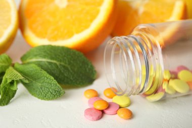 Vitamin hapları ve portakallar beyaz masada, yakın plan.
