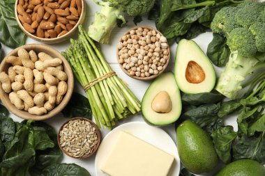 Farklı ürünler beyaz ahşap masa üzerinde E vitamini bakımından zengin, düz.
