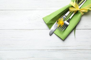 Çatal bıçak seti ve beyaz ahşap masa üzerinde güzel narsisler, yazı için yeri olan üst manzara. Paskalya kutlaması