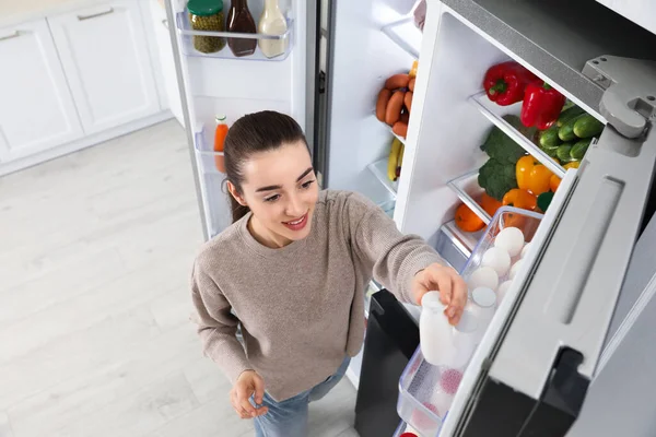 Mujer Joven Que Toma Yogur Hacia Fuera Refrigerador Interior Vista — Foto de Stock