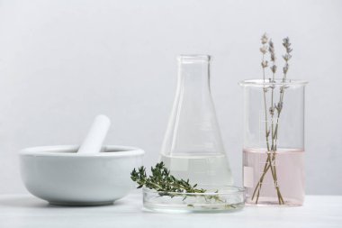 Beyaz masadaki bitkisel kozmetik ürünleri ve laboratuvar camları için malzemeler