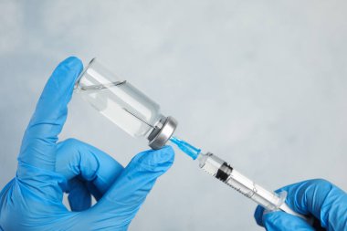 Şırıngayı hafif arka planda ilaçla dolduran doktor, yakın plan. Aşılama ve aşılama