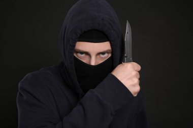 Siyah arka planda bıçağı olan maskeli bir adam. Tehlikeli suçlu.
