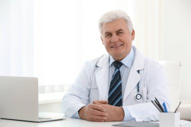 İş yerinde beyaz önlüklü kıdemli doktorun portresi.