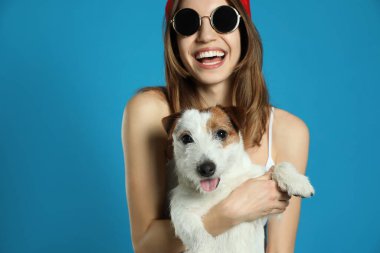 Açık mavi arka planda sevimli Jack Russell Terrier 'ı olan genç bir kadın. Sevimli hayvan