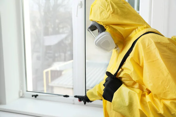 窓のまだ室内に殺虫剤を噴霧保護スーツの害虫駆除の労働者 — ストック写真