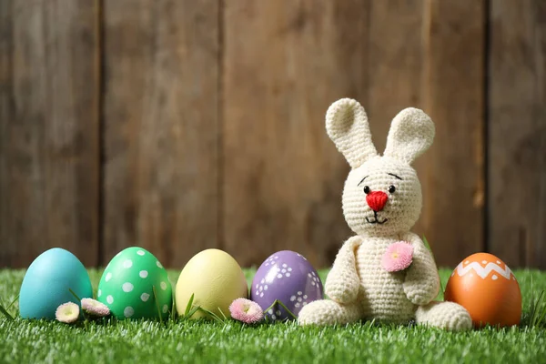 五彩缤纷的复活节彩蛋和绿色草地上木制背景的兔子玩具 — 图库照片