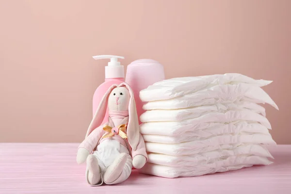 Babyluiers Speelgoedkonijntje Toiletartikelen Houten Tafel Tegen Roze Achtergrond — Stockfoto