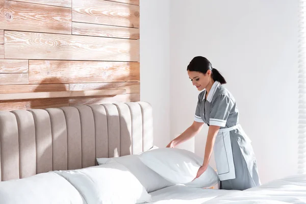 ホテルの部屋でベッドを作る若い女中 テキストのためのスペース — ストック写真