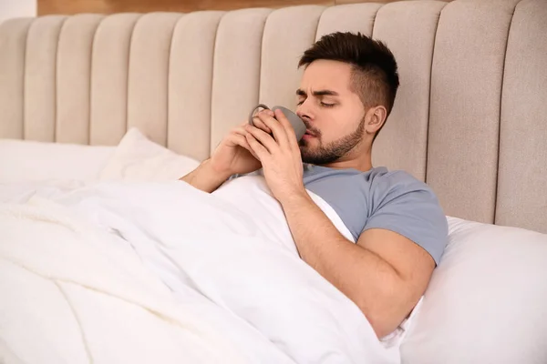 Kranker Junger Mann Mit Einer Tasse Heißgetränk Bett Hause Grippeviren — Stockfoto