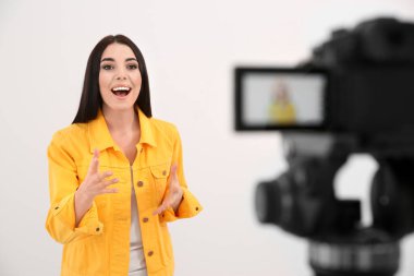 Genç blogcu beyaz arkaplana karşı kameraya video kaydediyor