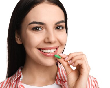 Beyaz arka planda vitamin kapsülü alan genç bir kadın.