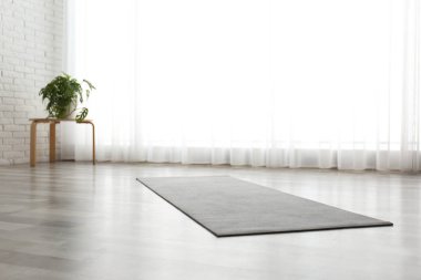 Odada yerde yuvarlanmış gri yoga minderi var.