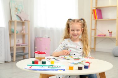 Cute little child painting at table in room
