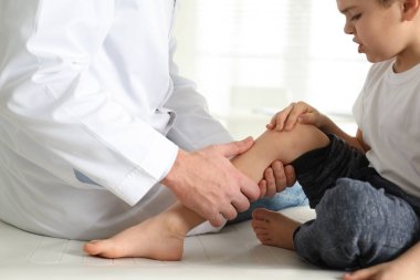 Klinikte küçük bir hastanın bacağını muayene eden profesyonel ortopedist.