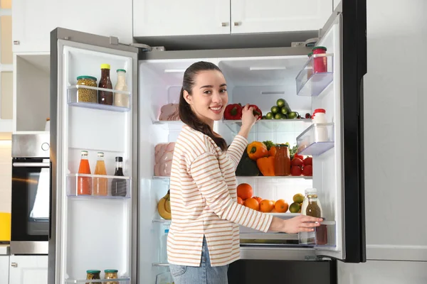 Jovem Mulher Tomando Pimentão Fora Geladeira Cozinha — Fotografia de Stock