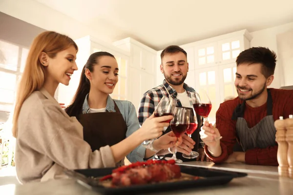Happy people drinking wine while cooking food in kitchen