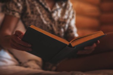 Evdeki yatakta kitap okuyan kadın, yakın çekim.