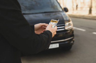 İş adamı şehir caddesinde akıllı telefonlu bir taksi istiyor.