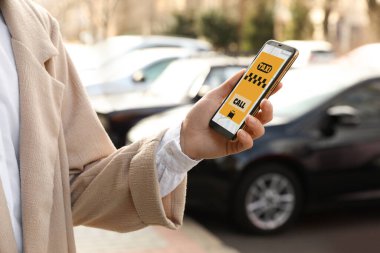 Şehir caddesinde akıllı telefondan taksi çağıran kadın, yakın plan.