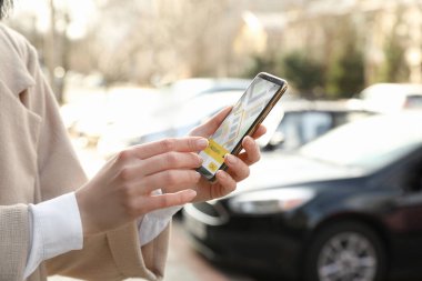 Woman ordering taxi with smartphone on city street, closeup clipart