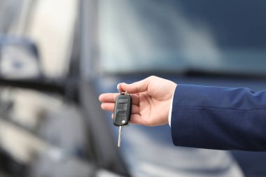 Modern oto galerisinde anahtarı elinde tutan adam, yakın plan. Yeni araba alınıyor
