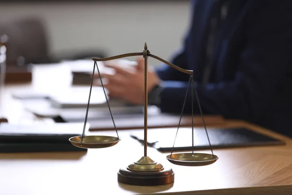 Scales of justice and blurred lawyer on background
