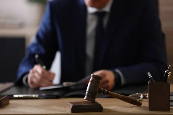 Male lawyer working at table in office, focus on gavel