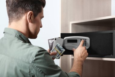 Otelde elektronik kilitle siyah çelik kasa açan adam.