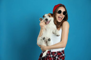 Açık mavi arka planda sevimli Jack Russell Terrier 'ı olan genç bir kadın. Sevimli hayvan