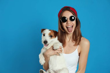 Açık mavi arka planda sevimli Jack Russell Terrier 'ı olan genç bir kadın. Sevimli hayvan