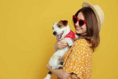 Sarı arka planda sevimli Jack Russell Terrier 'ı olan genç bir kadın. Mesaj için yer var. Sevimli hayvan