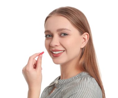 Beyaz arka planda vitamin kapsülü alan genç bir kadın.