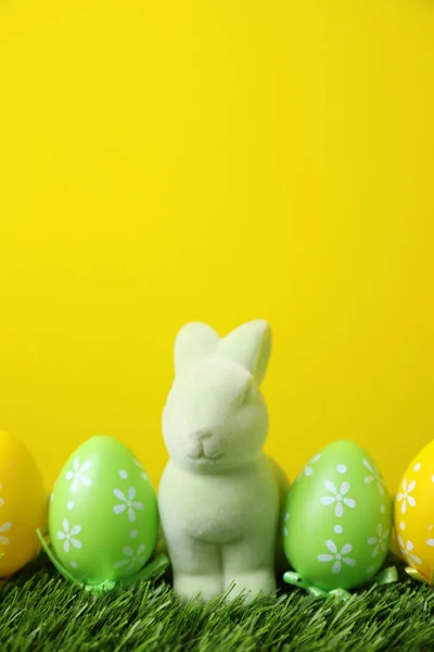 复活节兔子玩具和绿色草地上的彩蛋和黄色背景 案文的篇幅 — 图库照片