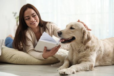 Kitaplı genç bir kadın ve evde onun Golden Retriever 'ı. Sevimli hayvan.